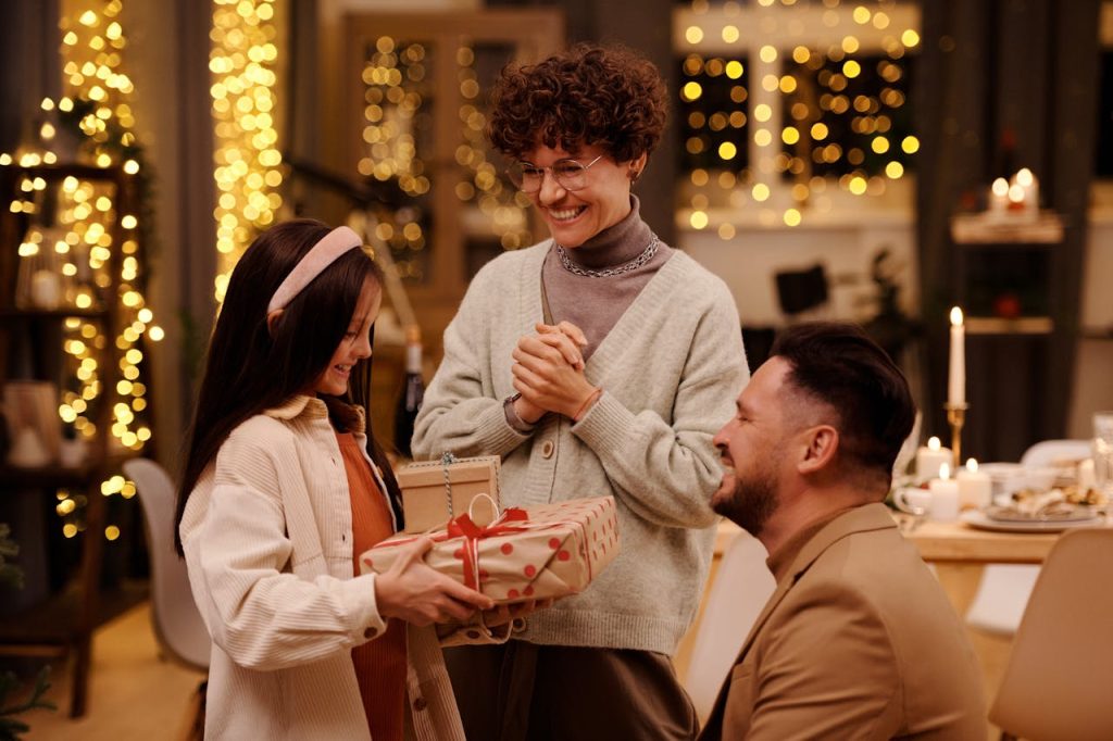A joyful family gathering exchanging gifts during a cozy Christmas evening indoors.